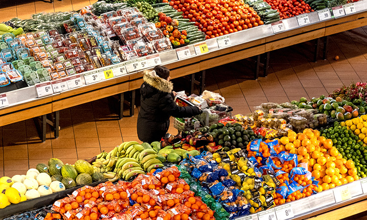 A person pushes a shopping cart through the produce section of a grocery store in Toronto, Ontario, Canada.
