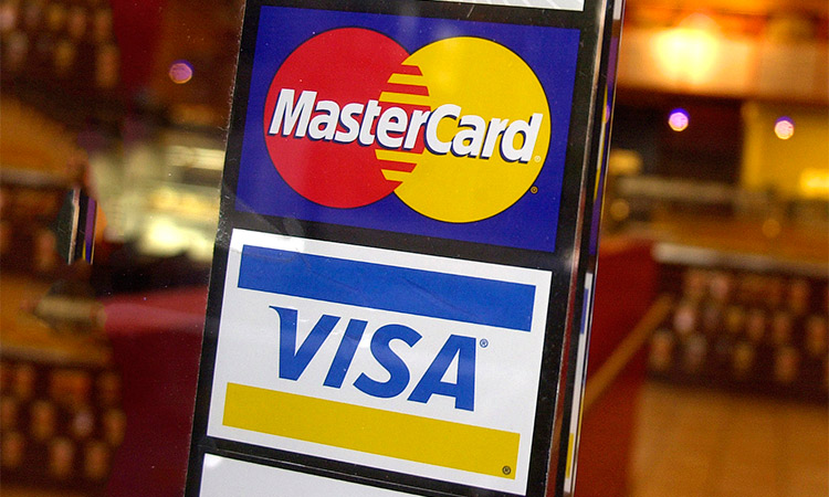 This photo shows logos for MasterCard and Visa credit cards at the entrance of a New York coffee shop.  AP