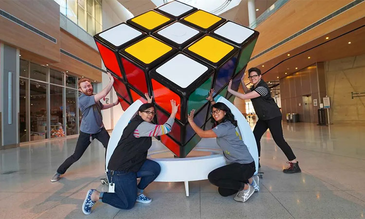 Students pose with a huge Rubik's Cube on display at a museum in Canada.