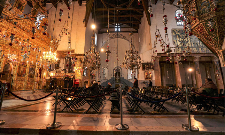 Christian worshippers sit in prayer before the iconostasis at the Greek Basilica in the Church of the Nativity in the biblical city of Bethlehem in the occupied West Bank early on Christmas Eve.     Agence France-Presse