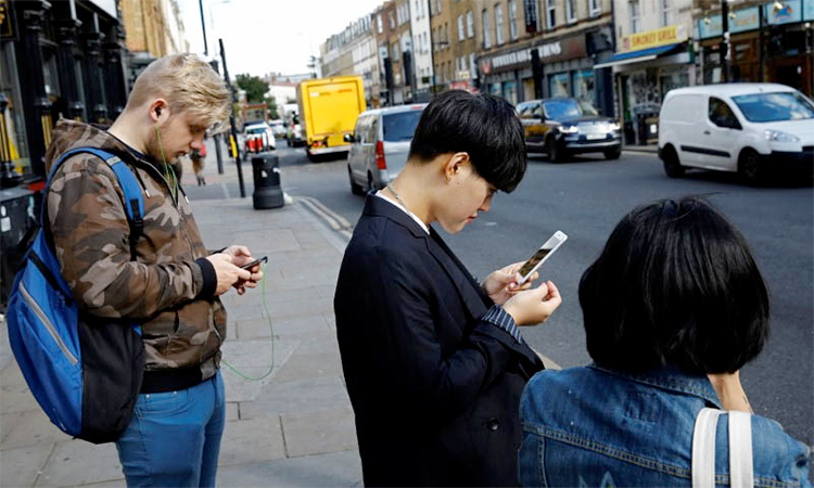 Pedestrians look at their mobile phones near Brick Lane in London.