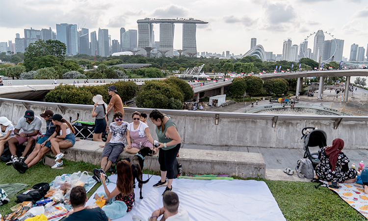 People picnic on the grassy roof of the Marina Barrage pumping station with a view of the Singapore skyline.