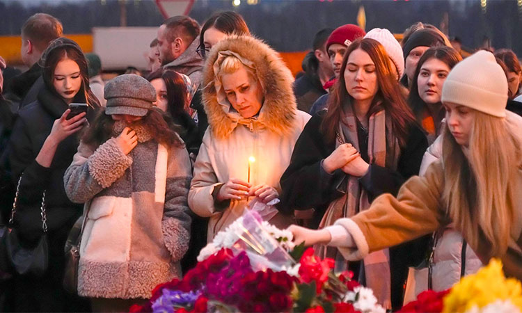 People lay flowers and light candles standing next to the Crocus City Hall, on the western edge of Moscow, Russia. AP