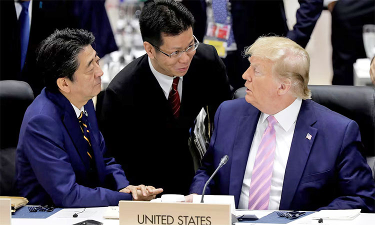 Sunao Takao (C) helps with translation as Japan's then-Prime Minister Shinzo Abe and then-US President Donald Trump talk in Osaka, Japan. File/Reuters