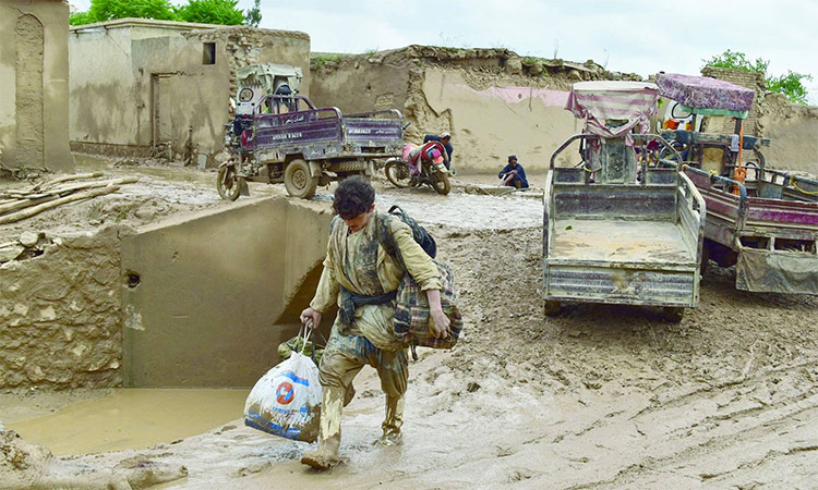 An Afghan man carries his belongings as he walks through a mud covered street following a flash flood after a heavy rainfall in Laqiha village of Baghlan-i-Markazi district in Baghlan province. AFP