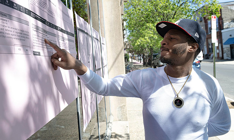 Jerome Upchurch reads voters information in Spanish, posted outside the Fleisher Art Memorial election polling place on on primary day last month in South Philadelphia. TNS