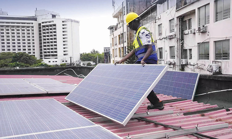 Oladapo Adekunle, an engineer with Rensource Energy, installs solar panels on a roof of a house in Lagos, Nigeria.  File/Associated Press