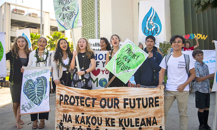 Youth plaintiffs and supporters hold up signs after the court hearing in Honolulu, Hawaiʻi. (Image via X)
