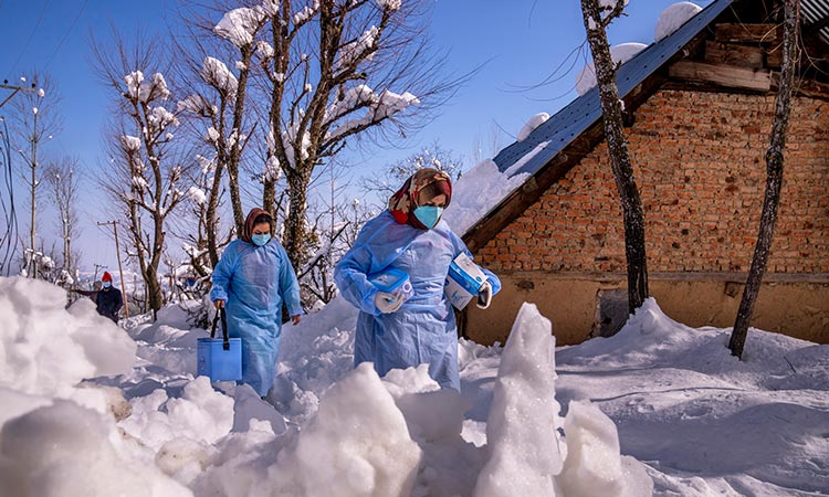 Vaccine workers trek in Kashmir's snowy mountains