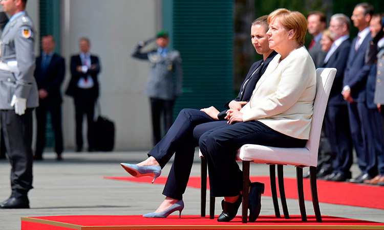 To prevent a repeat of uncontrollable  shaking Merkel sits during anthems