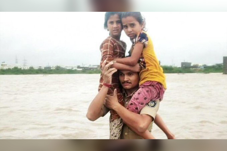 Watch how a Gujarat cop carries 2 kids on shoulder through floods